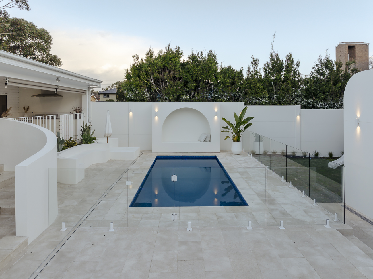 Frameless glass pool fence around a Mediterranean-style courtyard pool with white rendered walls at a Caringbah residence