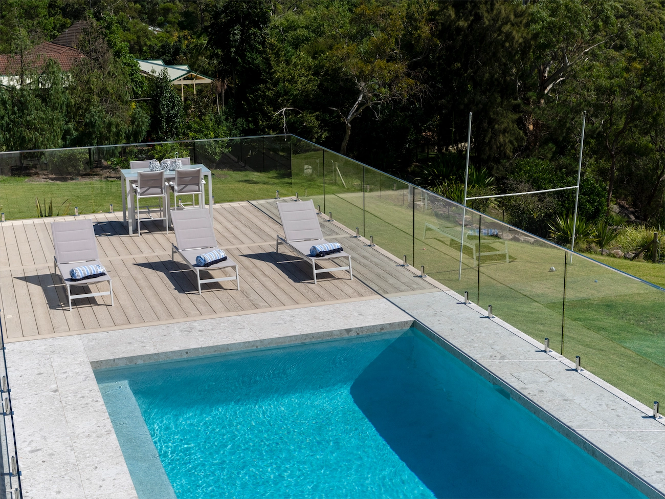 Frameless glass pool fence around a deck pool with bushland behind at a Kenthurst residence