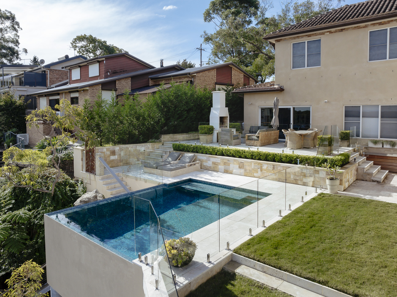 Frameless glass pool fence around a raised pool above the bush at a Berowra Heights residence