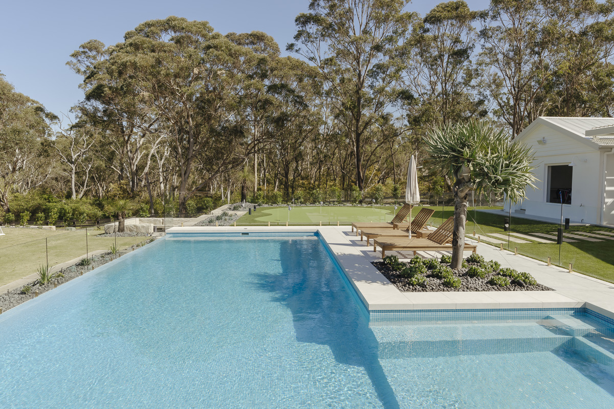 Frameless glass pool fence beside a large pool with bushland behind at an Annangrove residence