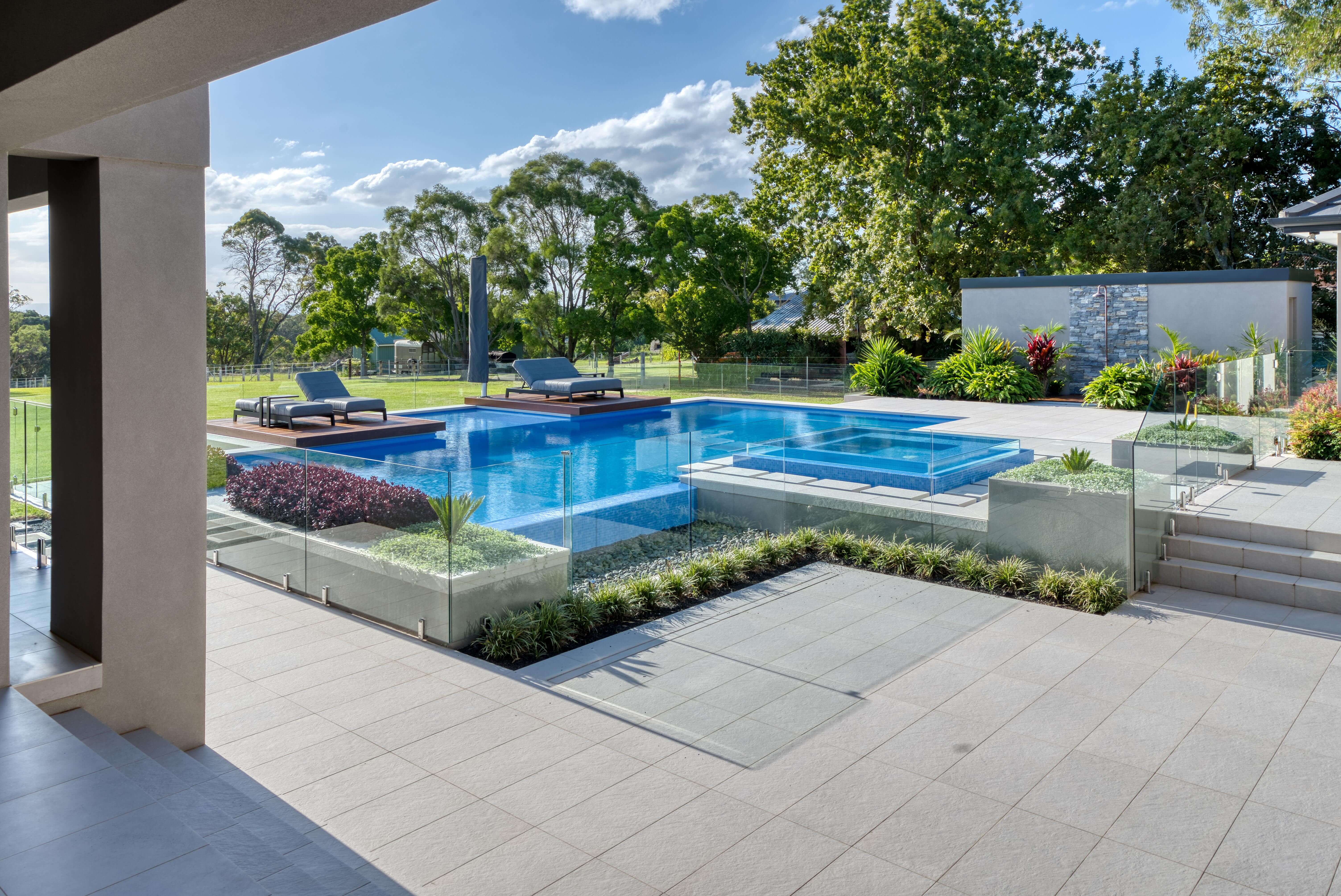Frameless glass pool fence beside an infinity-edge pool and spa, seen from the terrace of a Kenthurst residence