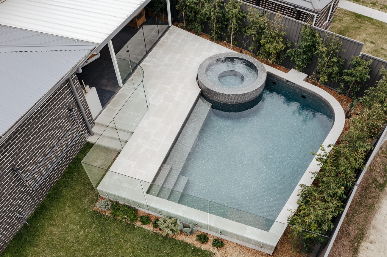Frameless glass fence around a pool and raised spa, seen from above, at a Colebee residence