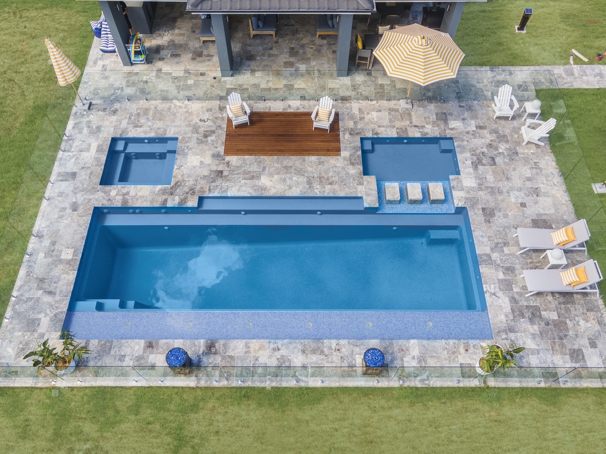 Frameless glass pool fence around a pool and spa beside a covered alfresco, seen from above, at a Twin Creeks residence