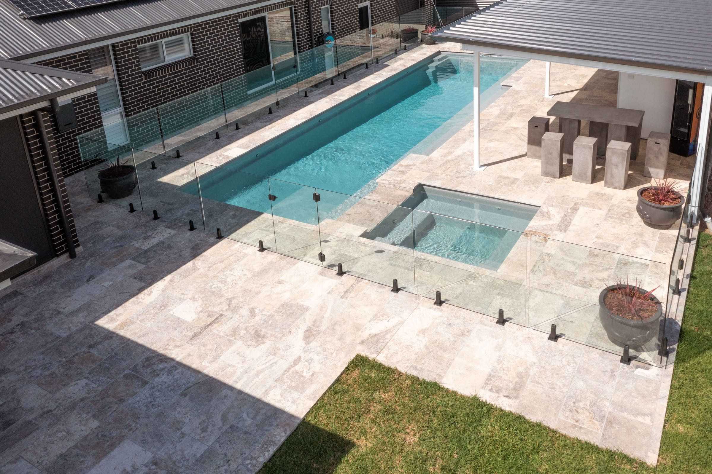Frameless glass fence around a lap pool and spa with a covered alfresco, seen from above, at a Silverdale residence