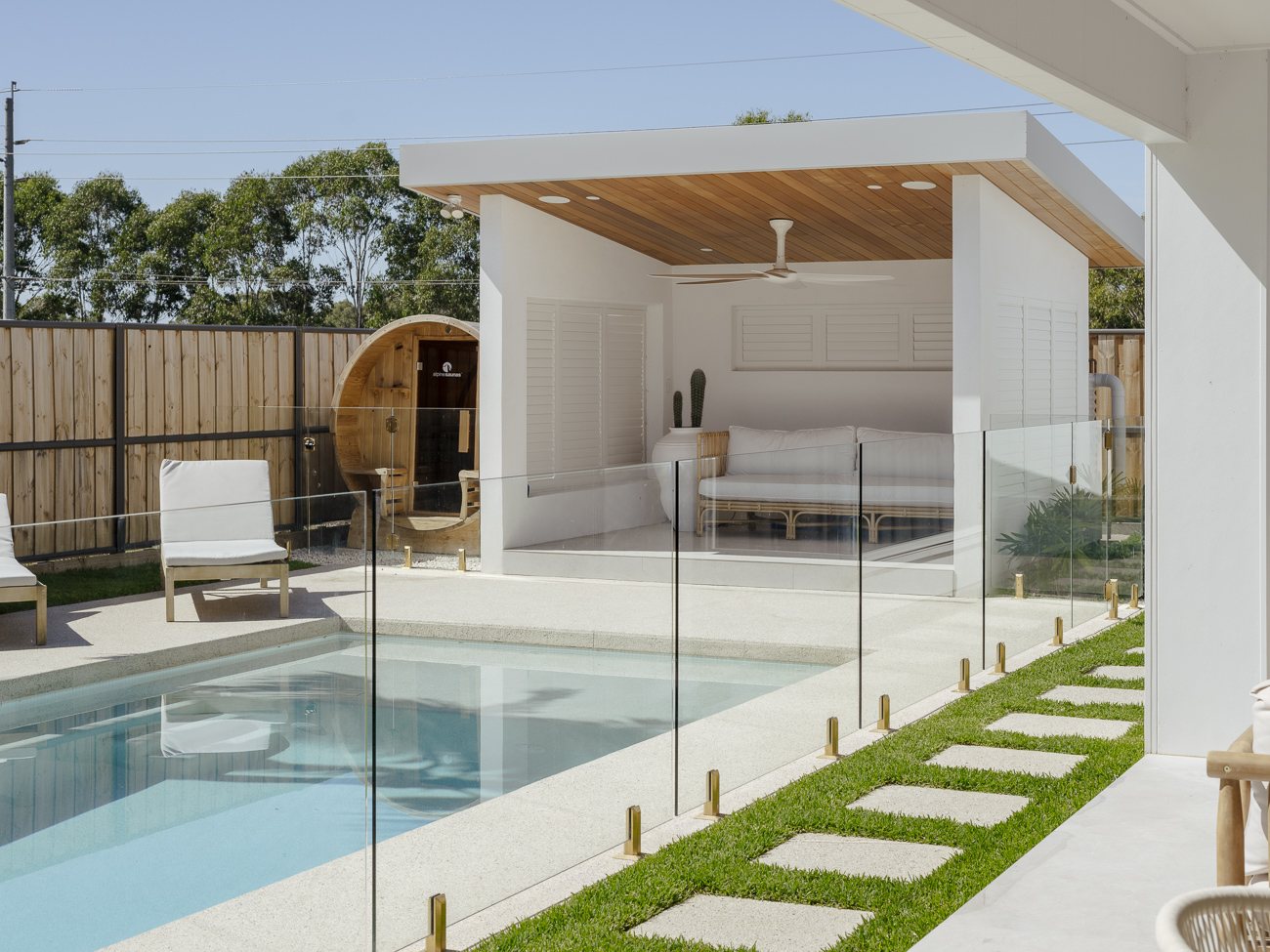 Frameless glass fence around a plunge pool in front of a white pavilion at a Wilberforce residence