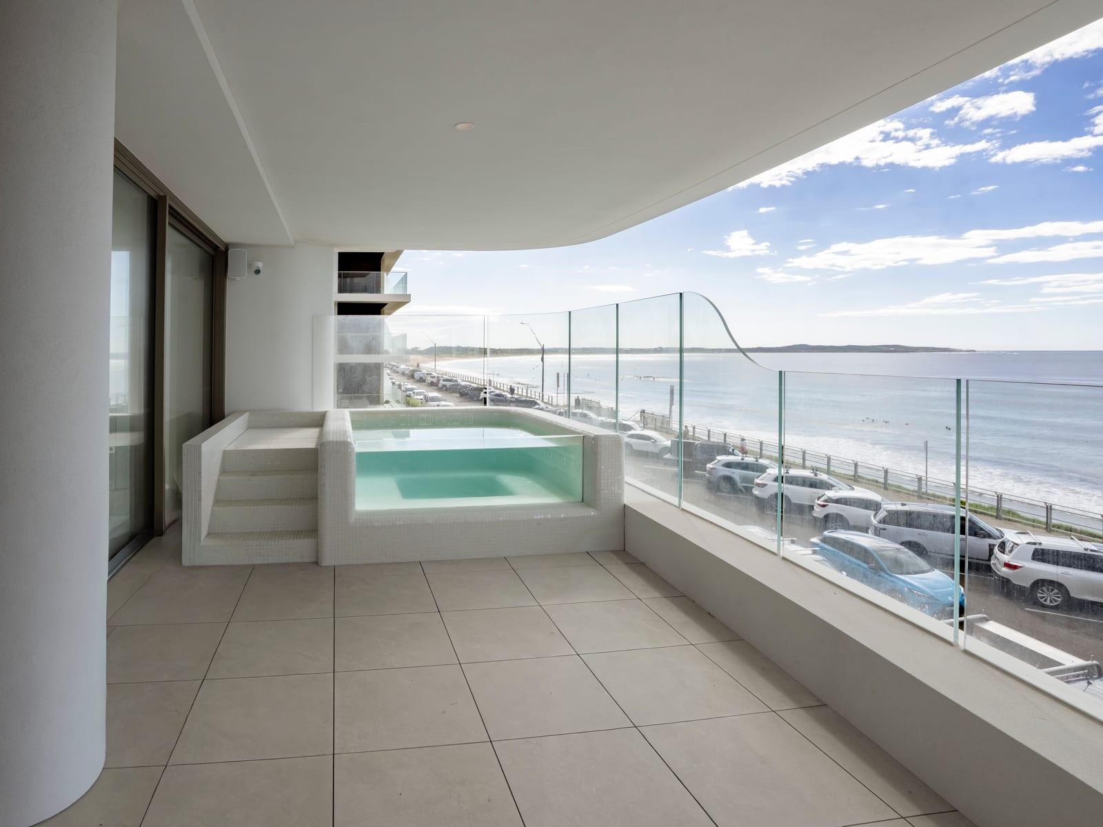 A curved glass balustrade and plunge pool on a Prince St, Cronulla balcony, looking out over the beach.