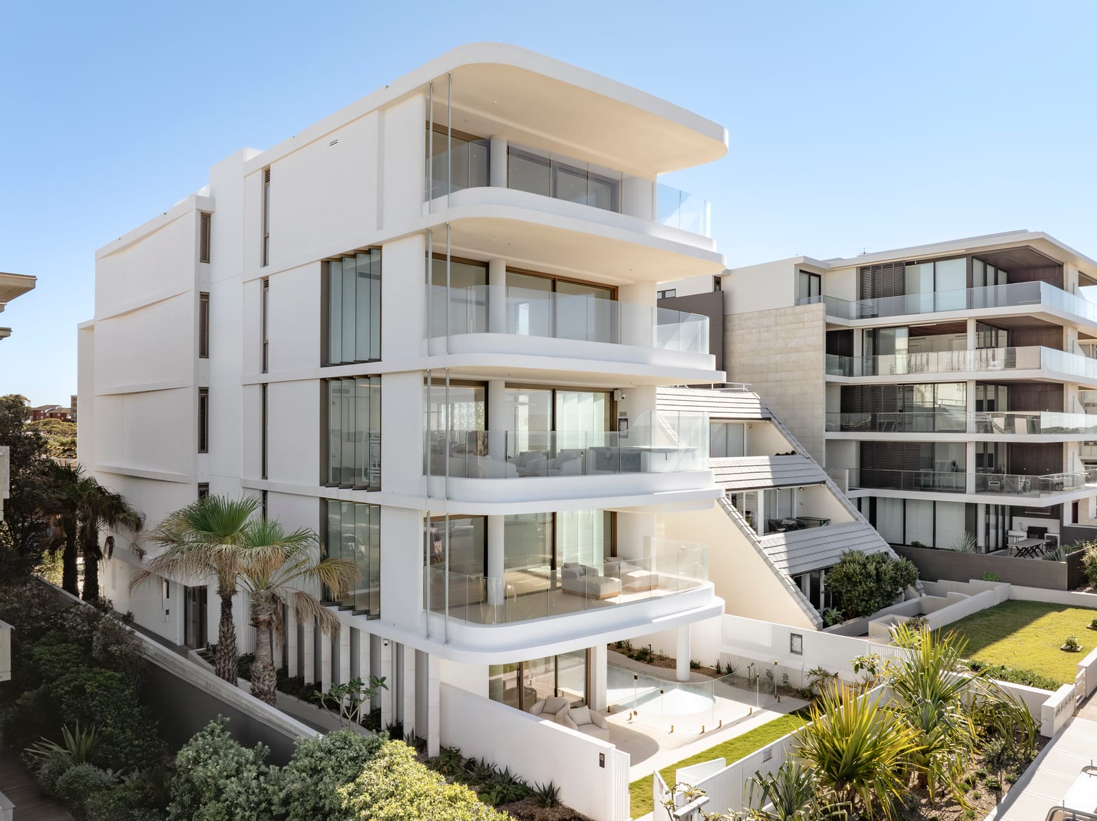 The Prince St, Cronulla apartment building with curved frameless glass balustrades following the rounded balconies of every level.